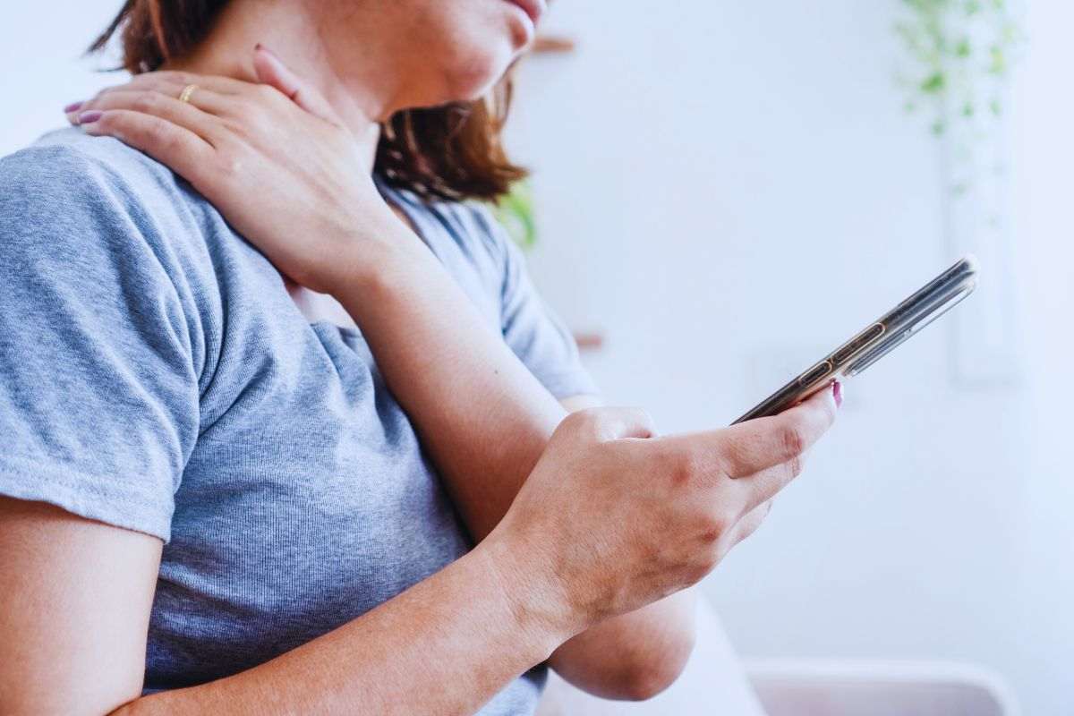 Donna con dolore cervicale che si fa un massaggio