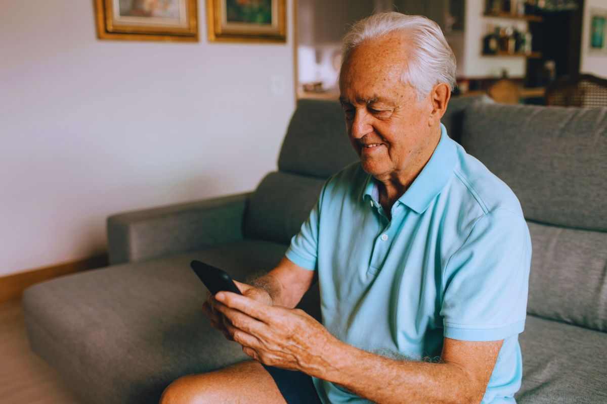 Anziano contento mentre osserva lo smartphone