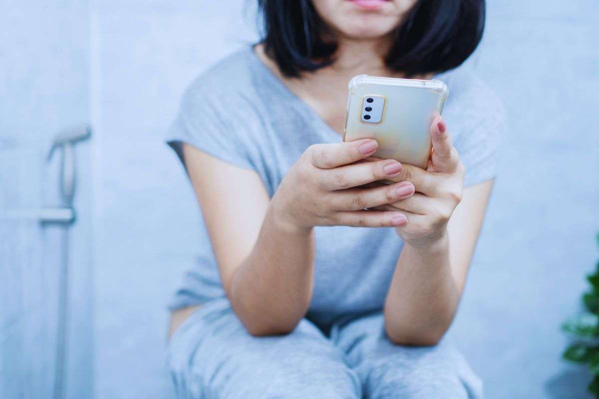 Donna che utilizza smartphone in bagno