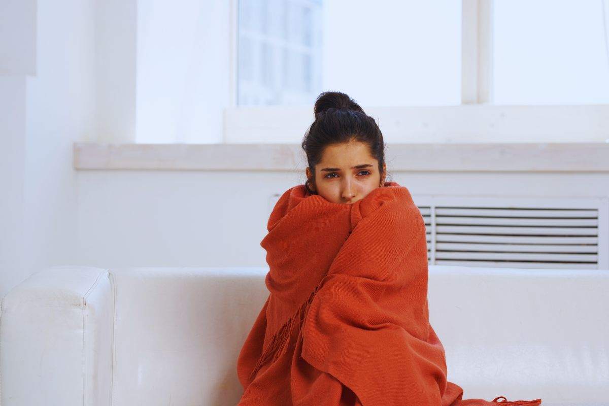 Ragazza infreddolita che si accuccia dentro una coperta