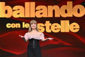Milly Carlucci in posa davanti al logo di Ballando con le Stelle