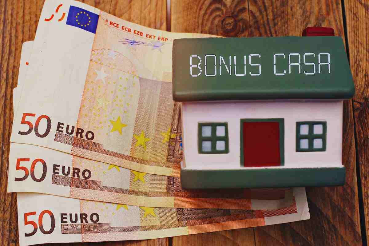 Banconote da 50 euro bloccati su scrivania da una miniatura di casa