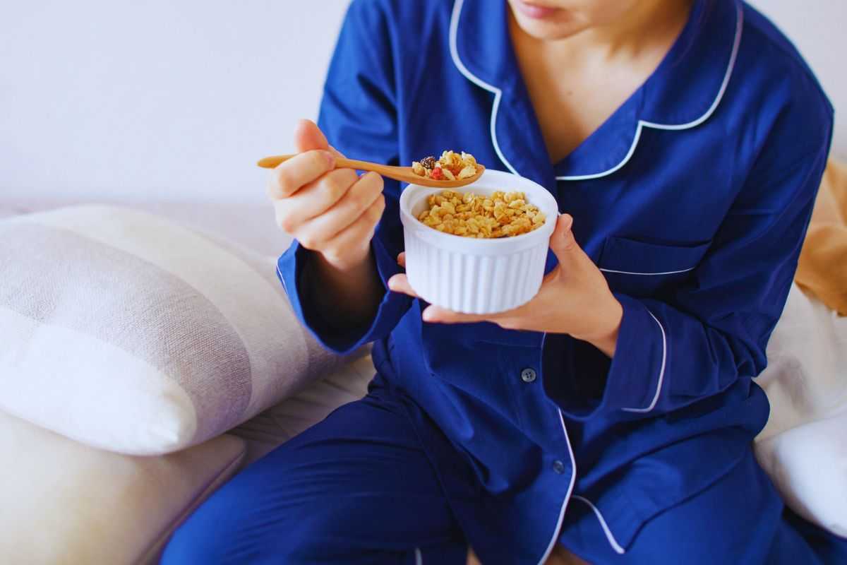 Donna in pigiama che mangia cereali