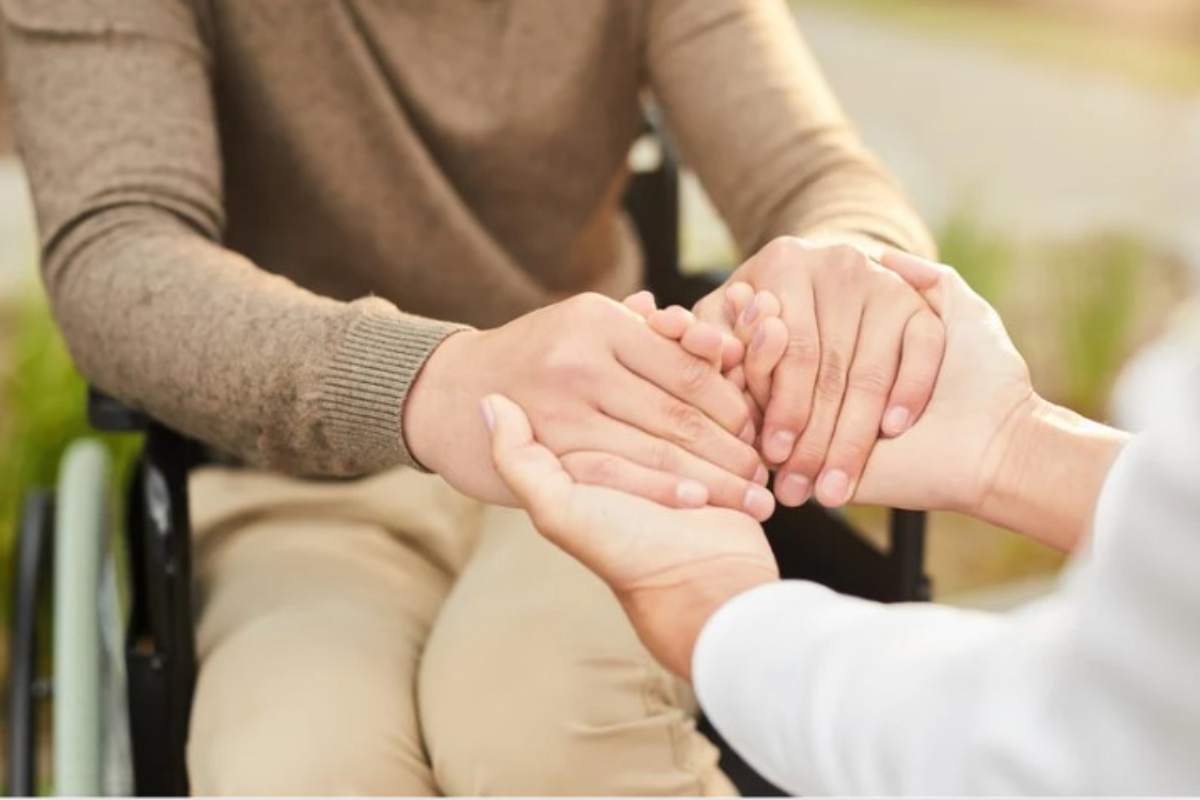 Assistente sociale tiene le mani ad un anziano 