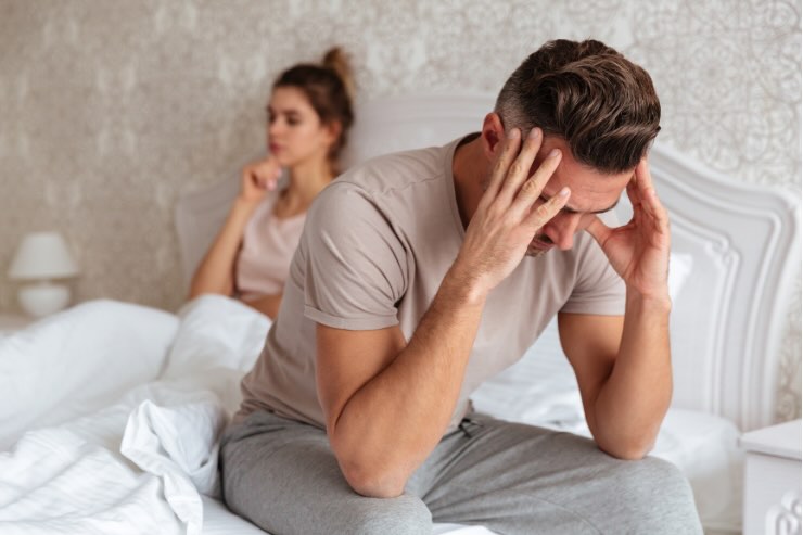 donna nel letto e uomo che si tocca tempie