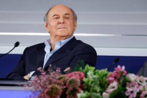 gerry scotti serio dietro i fiori