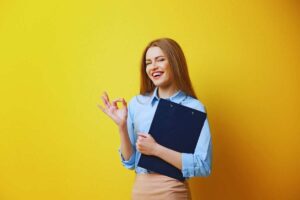 ragazza fa ok con la mano e ha una cartellina in mano
