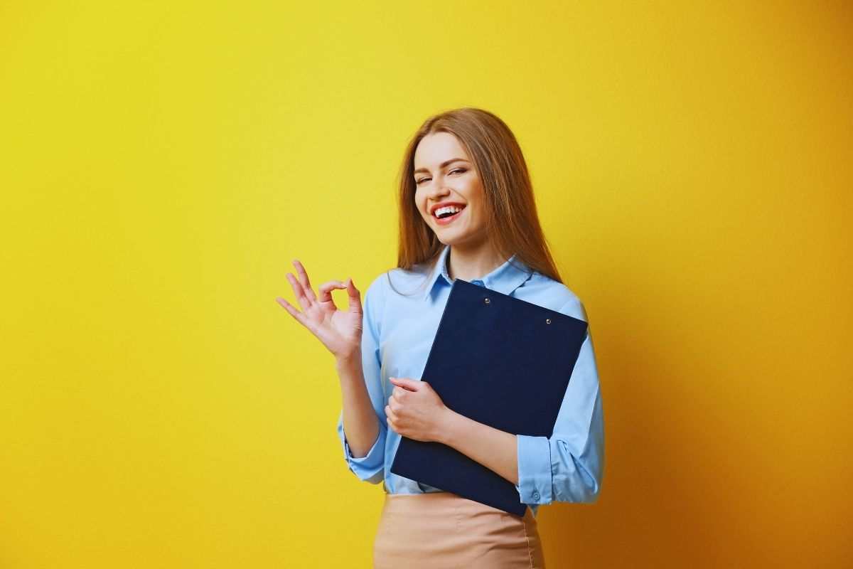 ragazza fa ok con la mano e ha una cartellina in mano