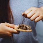Donna che rimuove i capelli incastrati nella spazzola