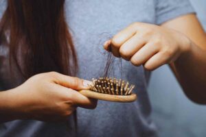 Donna che rimuove i capelli incastrati nella spazzola