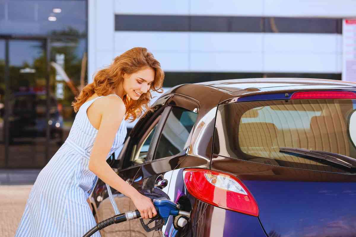 Ragazza sorridente che fa il pieno all'auto