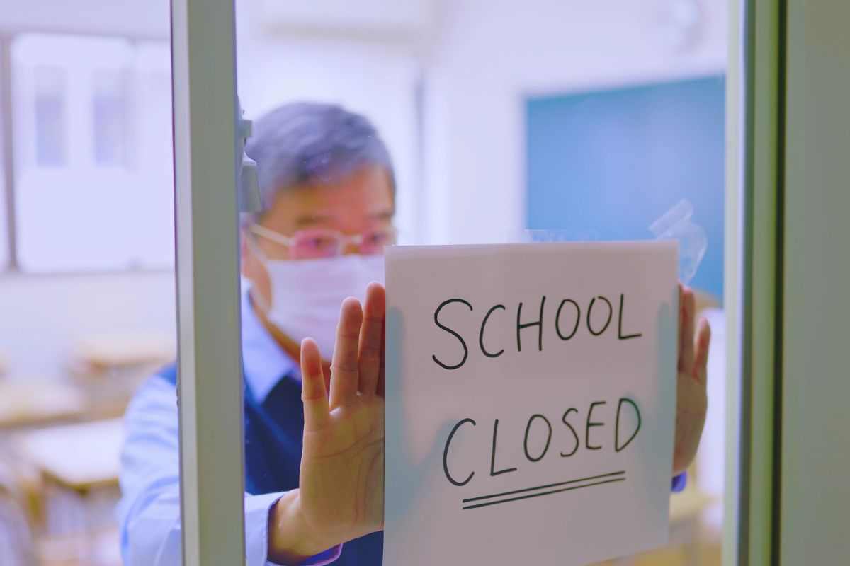 Insegnante che espone cartello "Scuola chiusa"