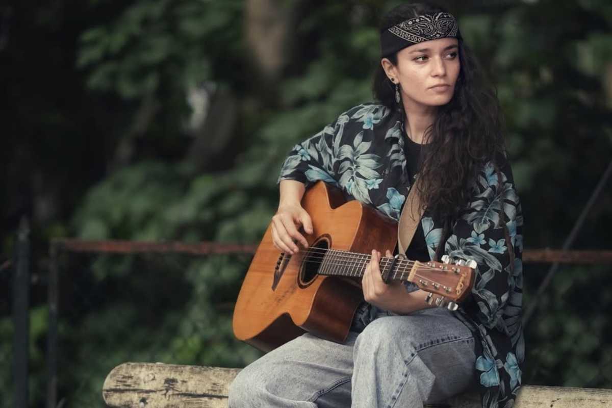 Nina Dusheck che suona la chitarra su una panchina del parco