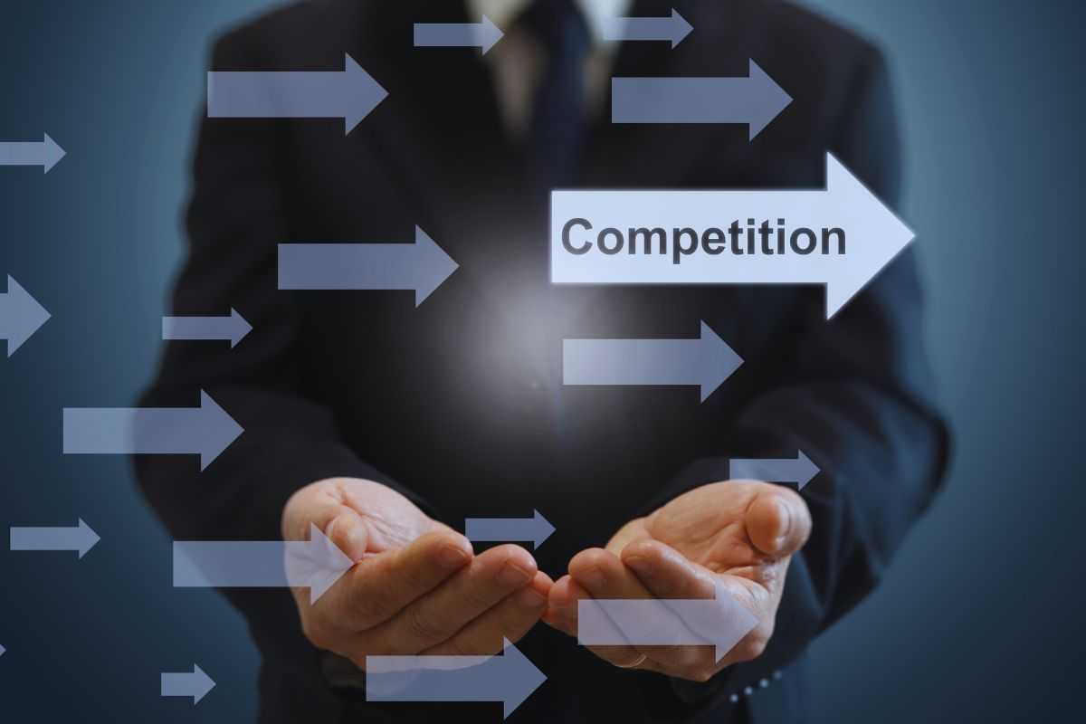 Uomo in abito e frecce su cui si legge la scritta competizione 