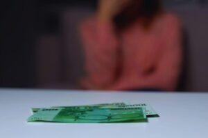 banconote poggiate su tavolo e donna sfocata sullo sfondo