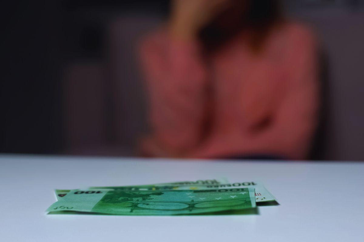 banconote poggiate su tavolo e donna sfocata sullo sfondo