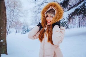 Ragazza sorridente in mezzo ad un bosco innevato