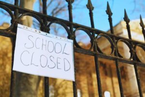 Grata di ferro e cartello con scritto "School Closed"